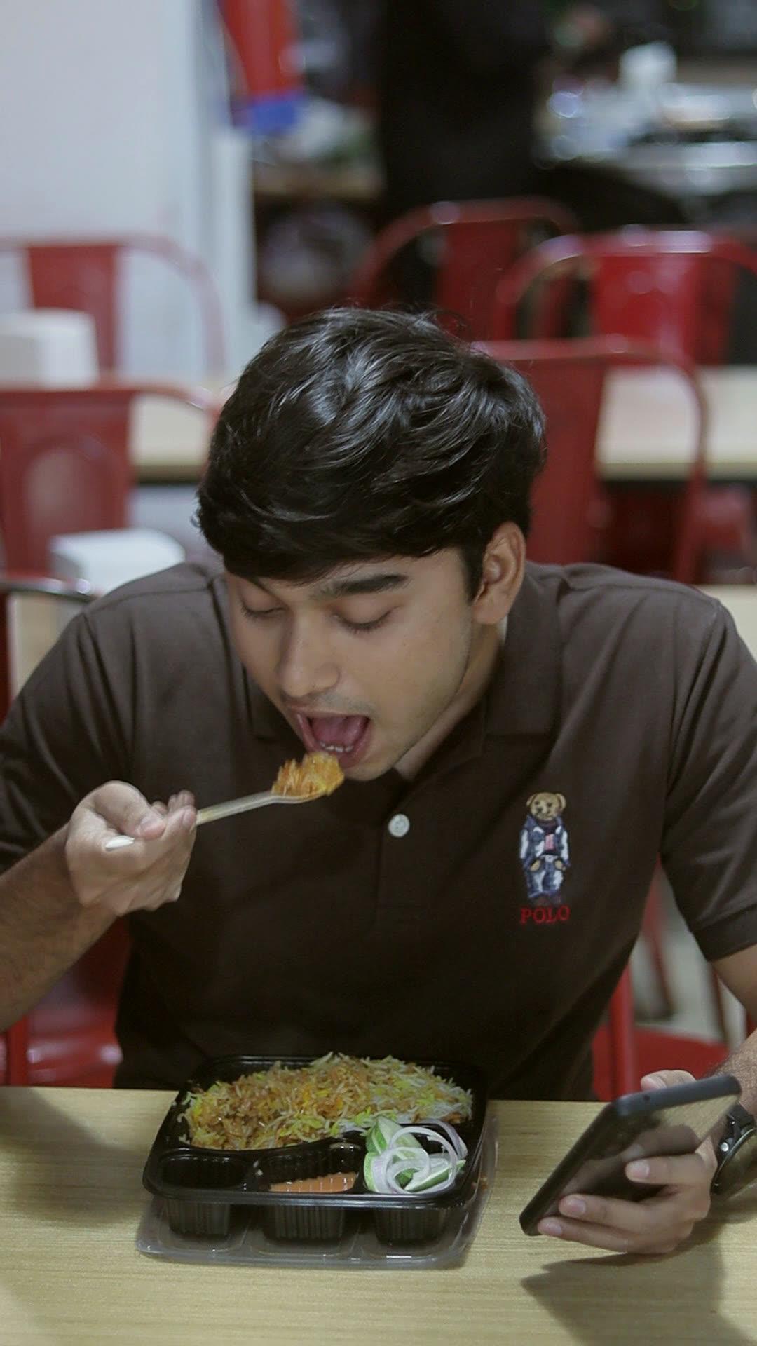 Guest taking an eager first bite of biryani at an office lunch